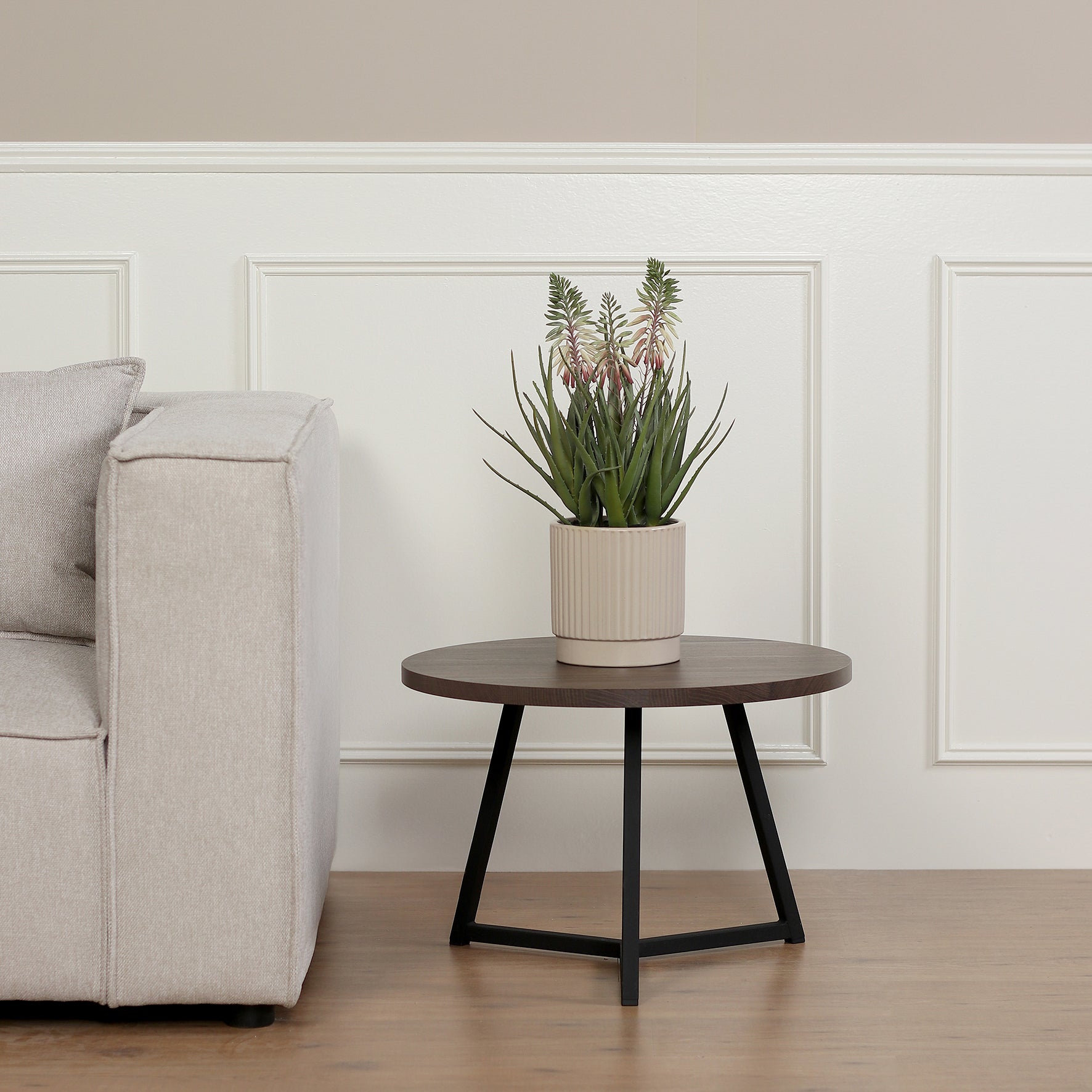 Künstliche Aloe von Lumisa’s Choice in beigem Keramiktopf auf rundem Beistelltisch neben Sofa.