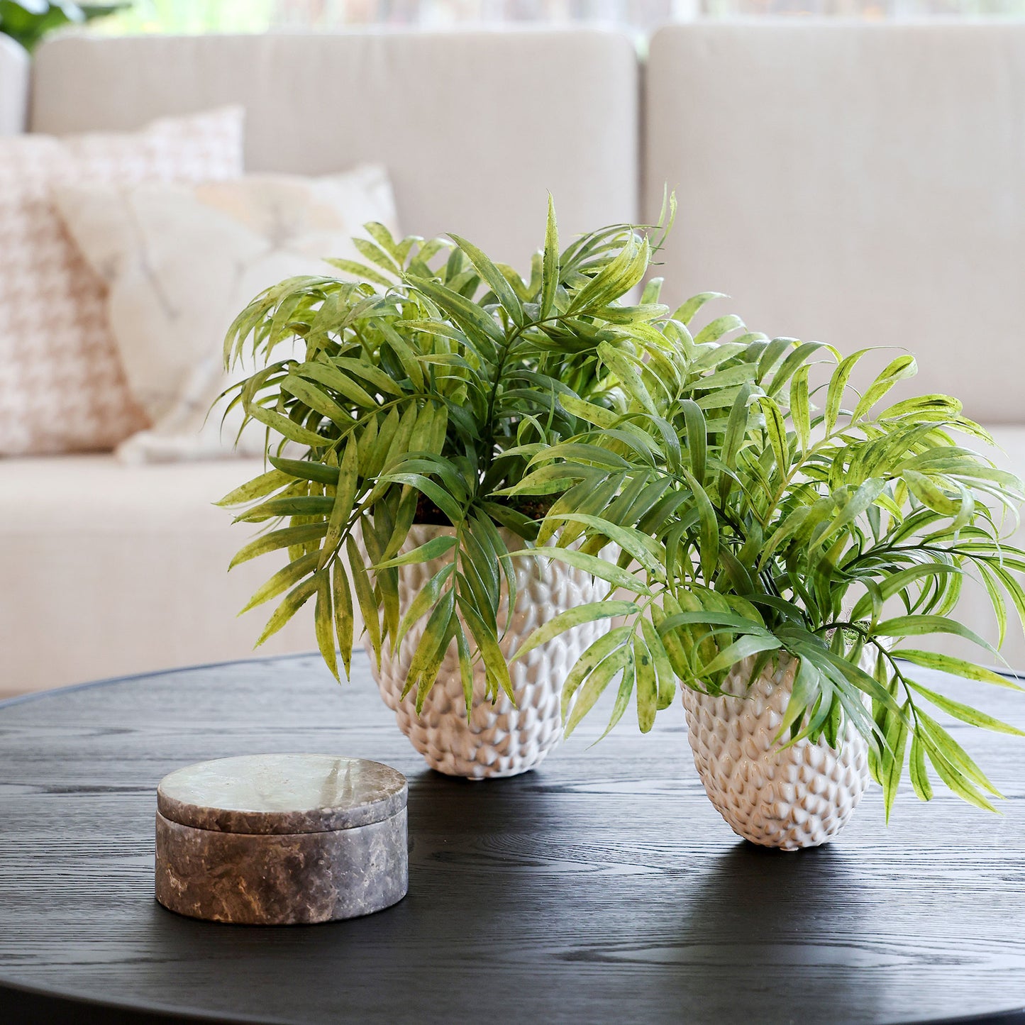 Zwei künstliche Chico-Pflanzen im Set in weißen Keramiktöpfen Lumisa’s Choice auf Beistelltisch im Wohnzimmer