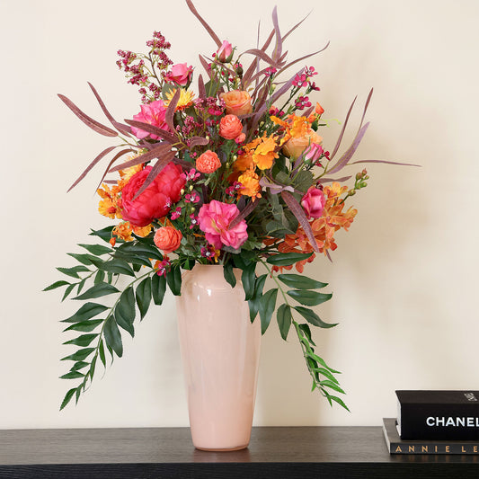 Künstlicher Blumenstrauß Flower Cocktail von Lumisa’s Choice in kräftigen Farben in  apricot farbener Vase als moderne Dekoration auf schwarzen Sideboard.