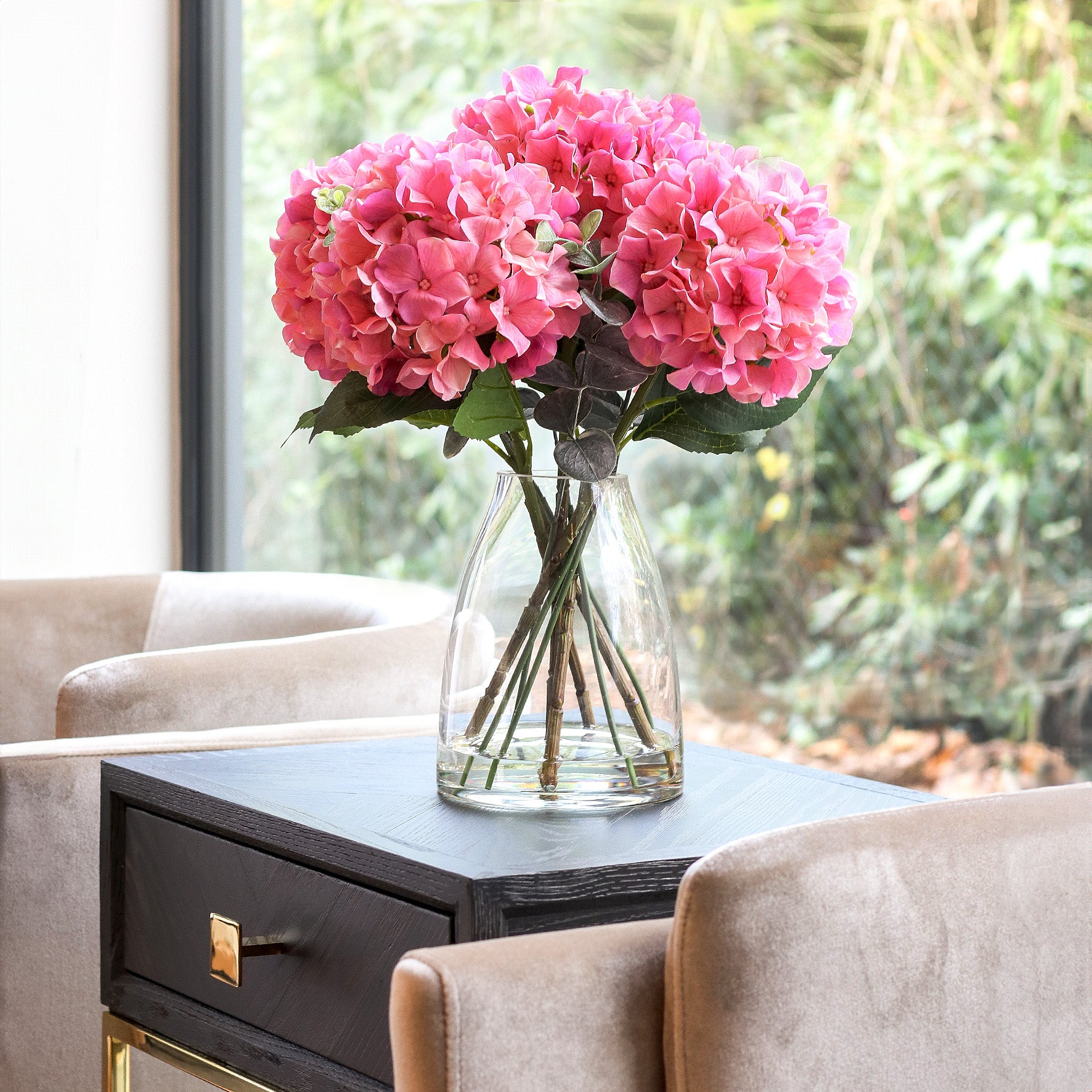 Künstliche pinke Hortensie in Glasvase im hochwertigen Interior