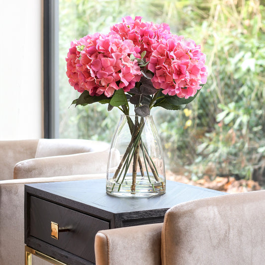 Künstliche pinke Hortensie in Glasvase im hochwertigen Interior
