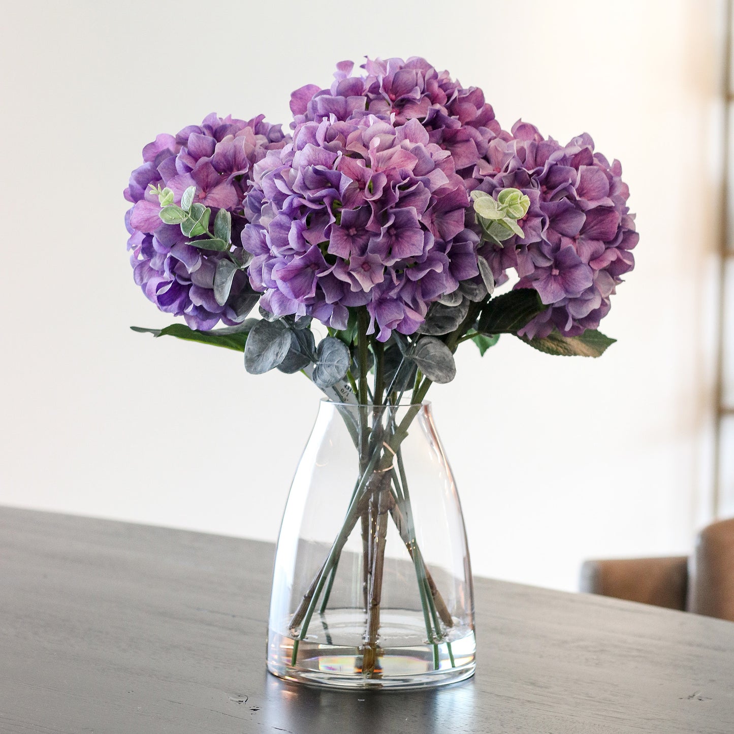 Künstliche violette Hortensie in Glasvase im hochwertigen Interior