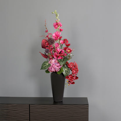 Künstlicher Blumenstrauß Pink Passion von Lumisa’s Choice in kräftigen Pinktönen in schwarzer Vase  als moderne Dekoration vor grauer Wand.