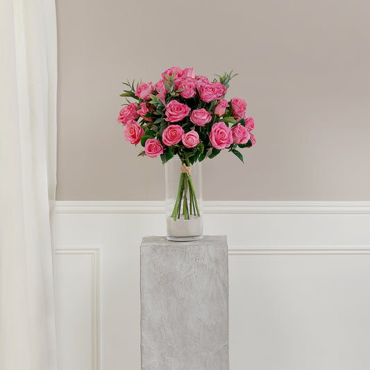 Künstlicher Blumenstrauß Rose Mono Bouquet Pink von Lumisa’s Choice mit pinkfarbenen Blüten und Olivenzweigen als elegante Dekoration vor heller Wand.