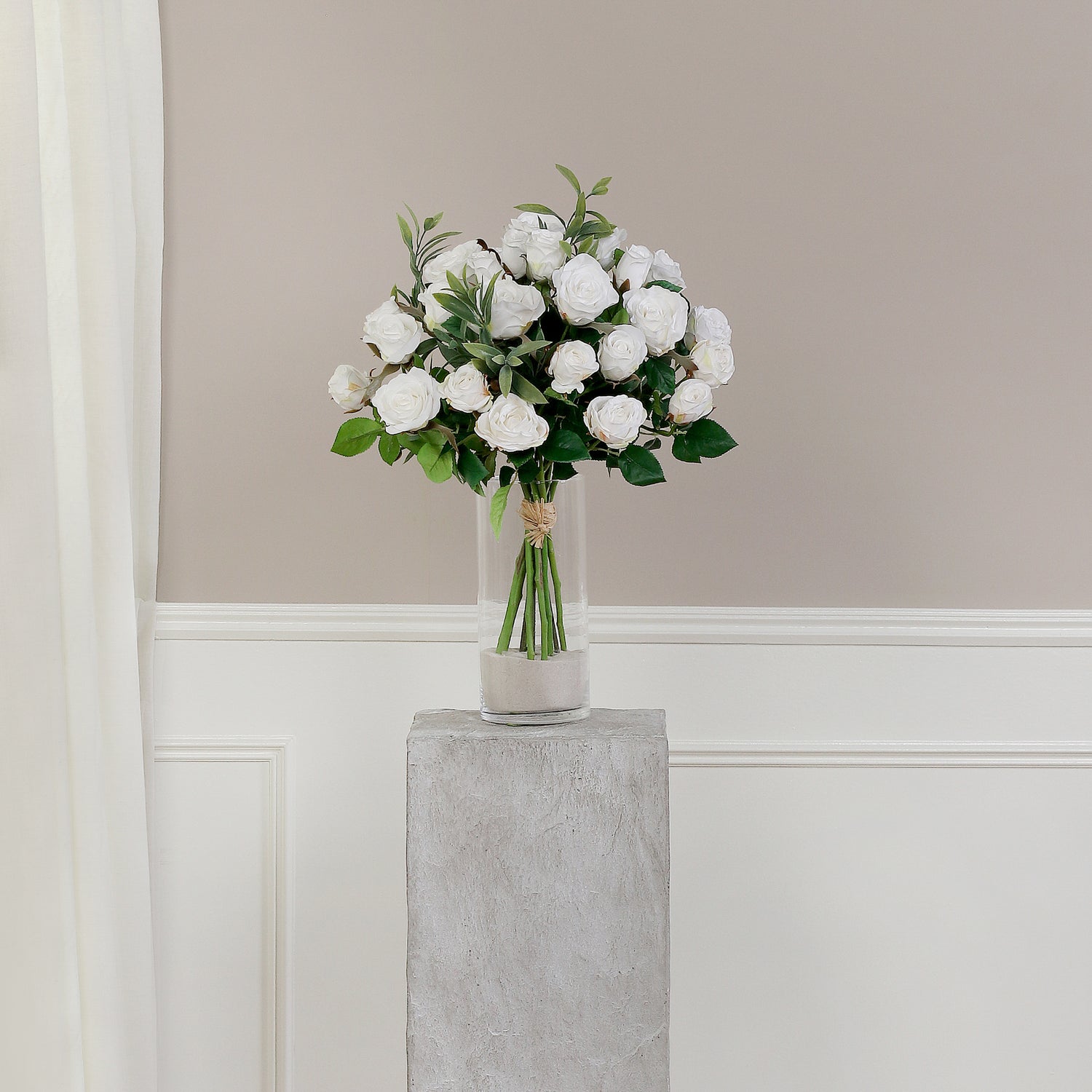 Künstlicher Blumenstrauß Rose Mono Bouquet White von Lumisa’s Choice mit weißen Blüten und Olivenzweigen als elegante Dekoration auf grauem Sockel vor heller Wand.