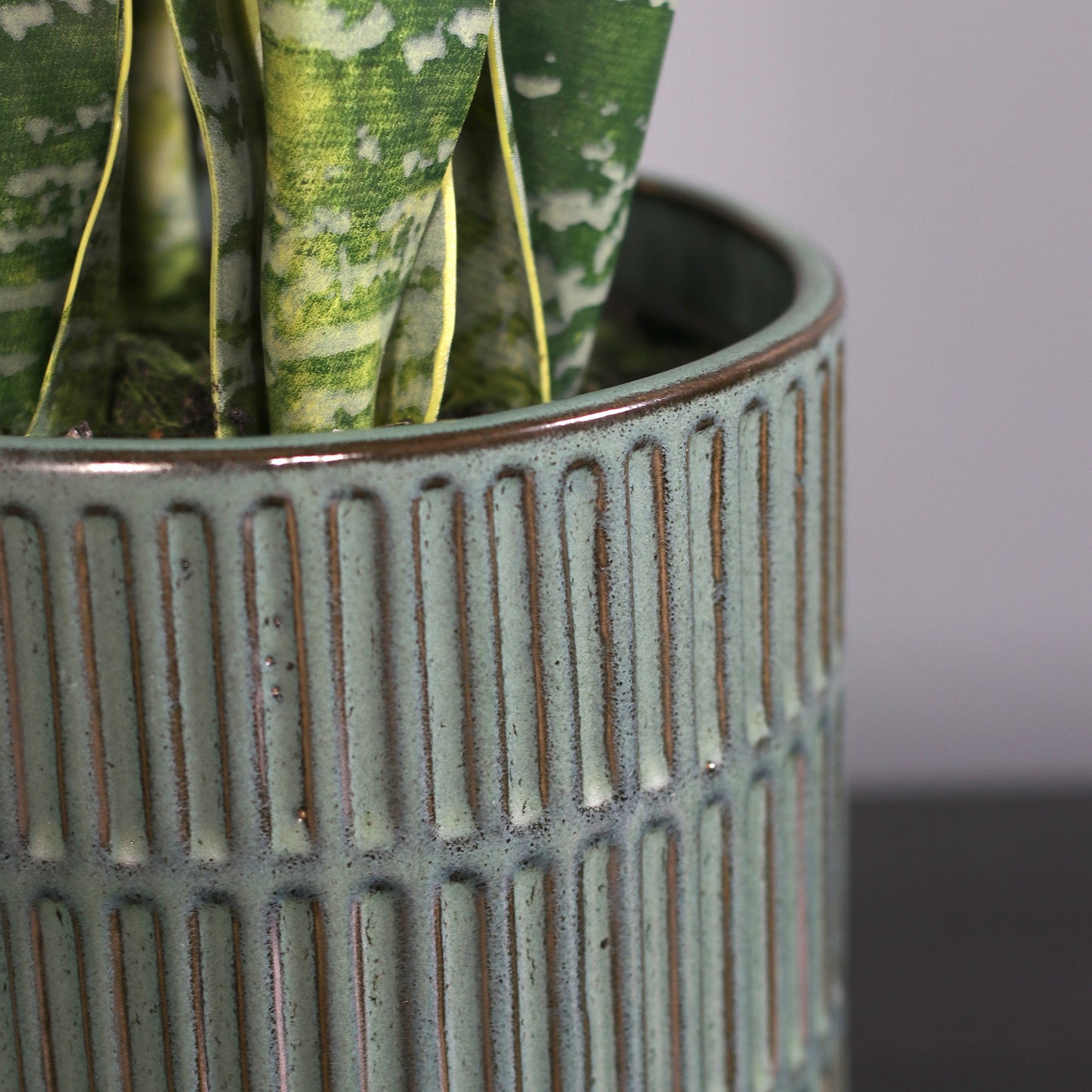Detailbild vom Topf der künstlichen Grünpflanze Sansevieria in grünem Keramiktopf von Lumisa’s Choice.