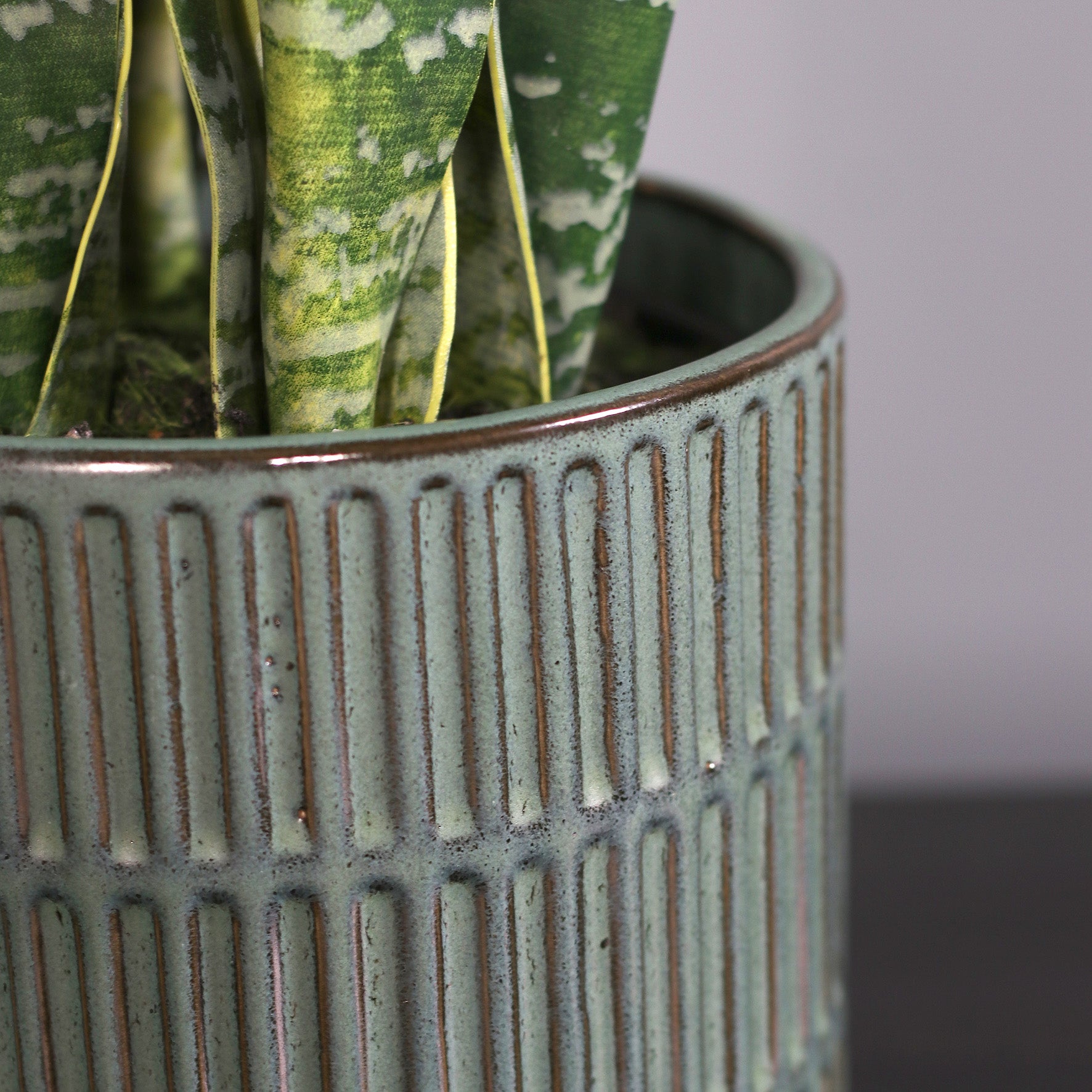Detailbild vom Topf der künstlichen Grünpflanze Sansevieria in grünem Keramiktopf von Lumisa’s Choice.