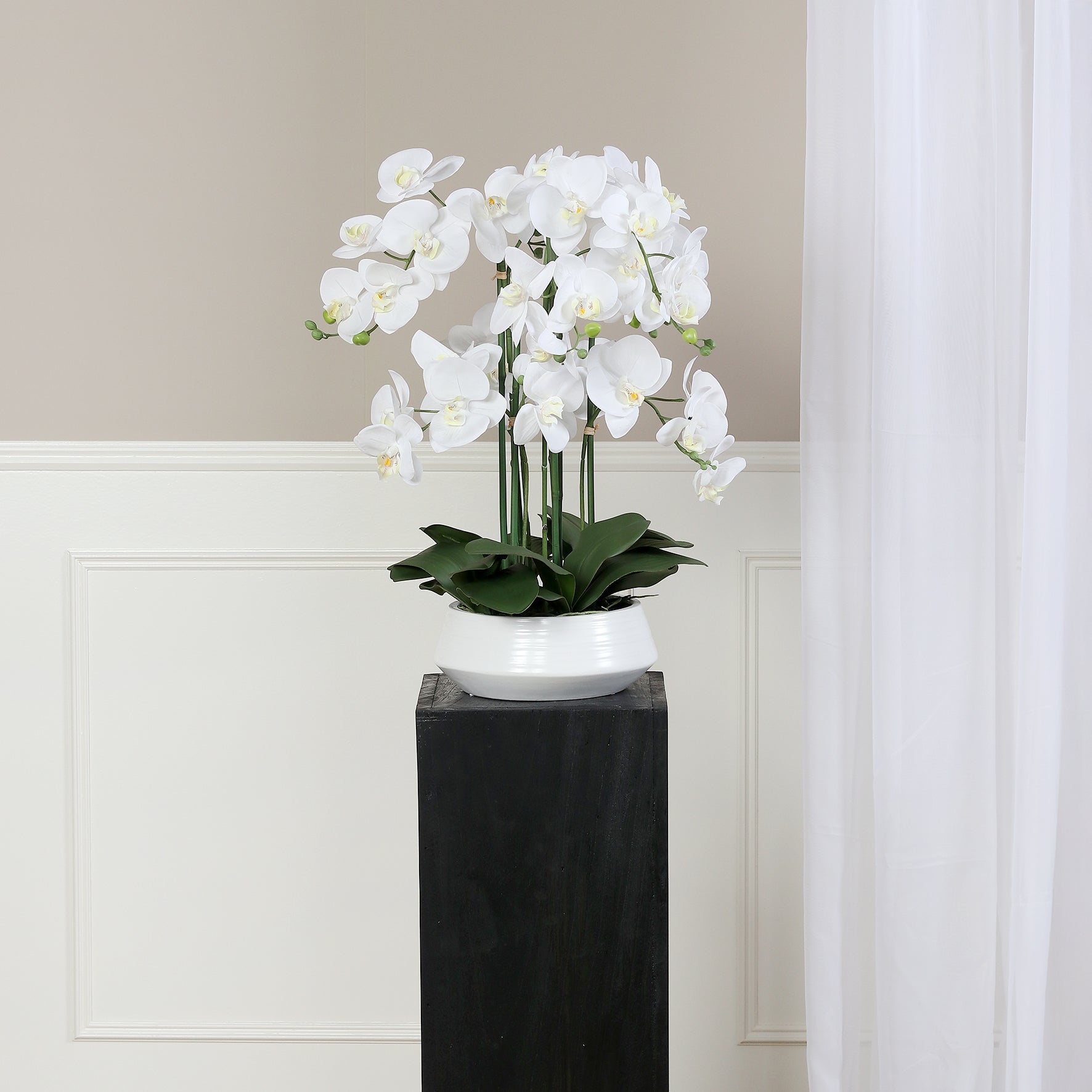 Künstliche Signature Orchidee klein mit stylischem Topf auf Podest im Interior