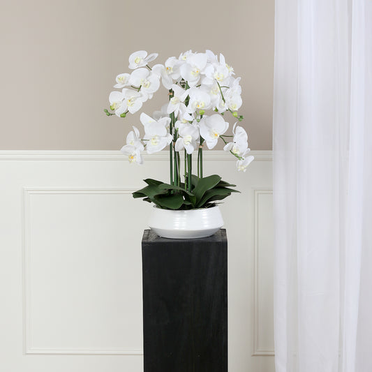 Künstliche Signature Orchidee klein mit stylischem Topf auf Podest im Interior
