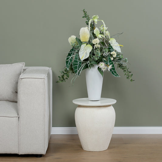 Künstlicher Blumenstrauß Soul of Nature von Lumisa’s Choice in Grün- und Weißtönen in eleganter weißer Vase auf Beistelltisch neben hellem Sofa.
