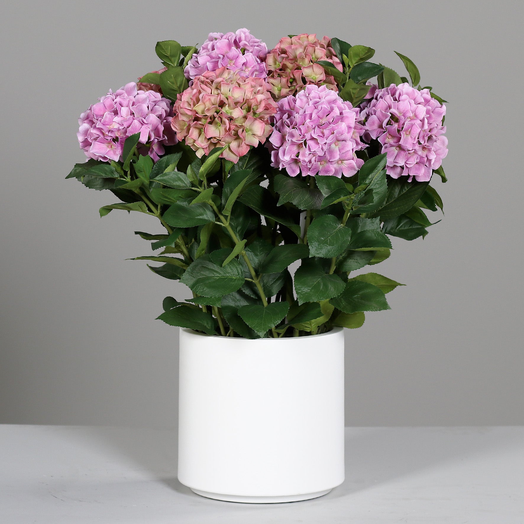 Großes künstliches Premium Hortensien-Arrangement im Topf pink auf Tisch