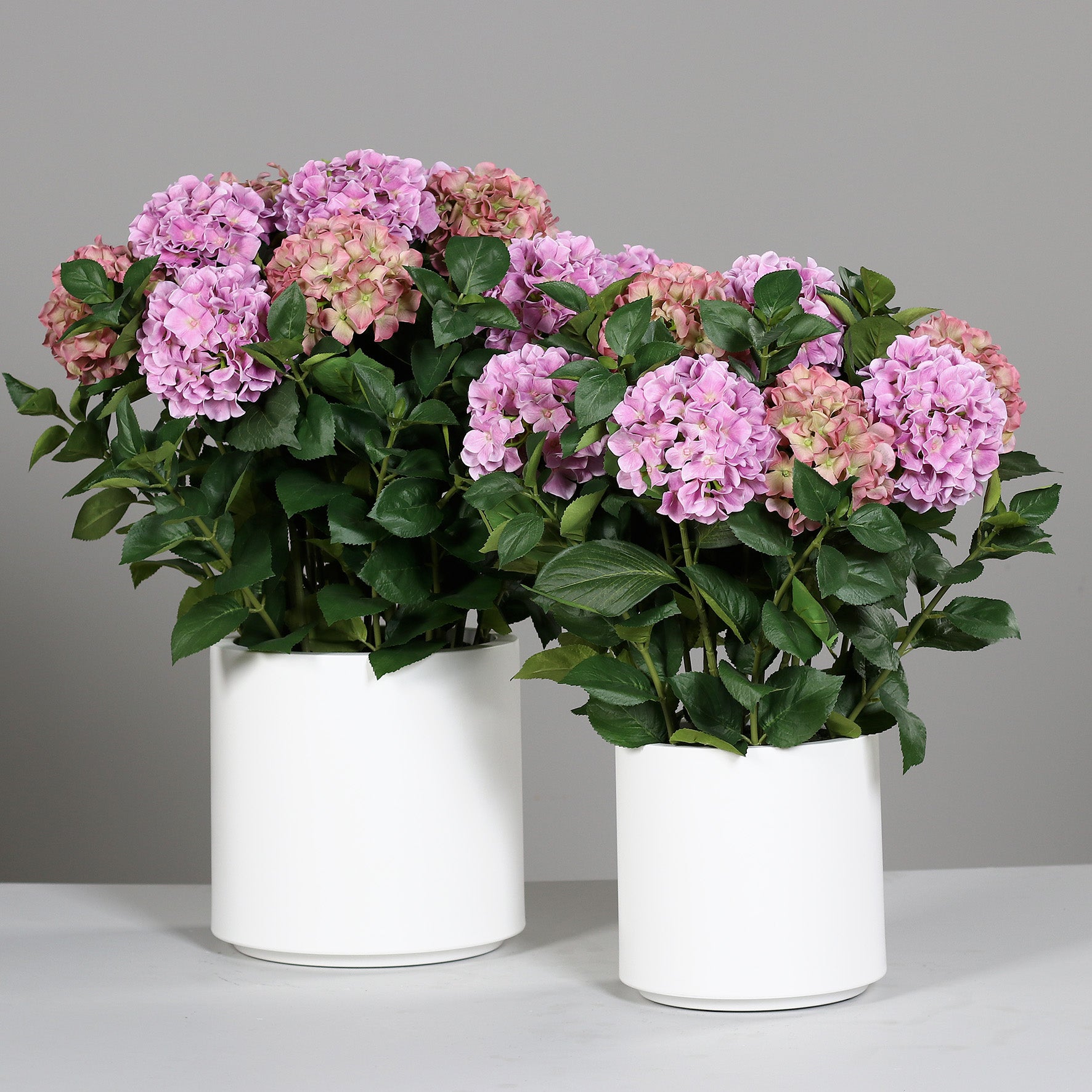 Zwei künstliche Premium Hortensien-Arrangements im Topf pink auf Tisch