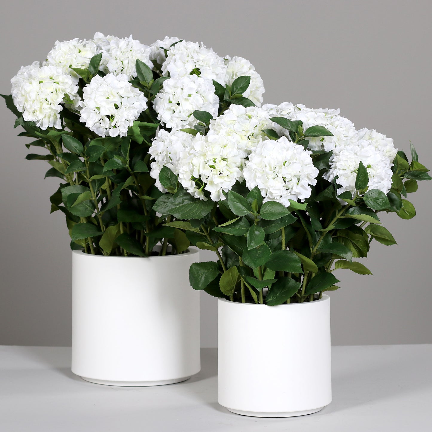 Zwei künstliche Premium Hortensien-Arrangements im Topf weiß auf Tisch