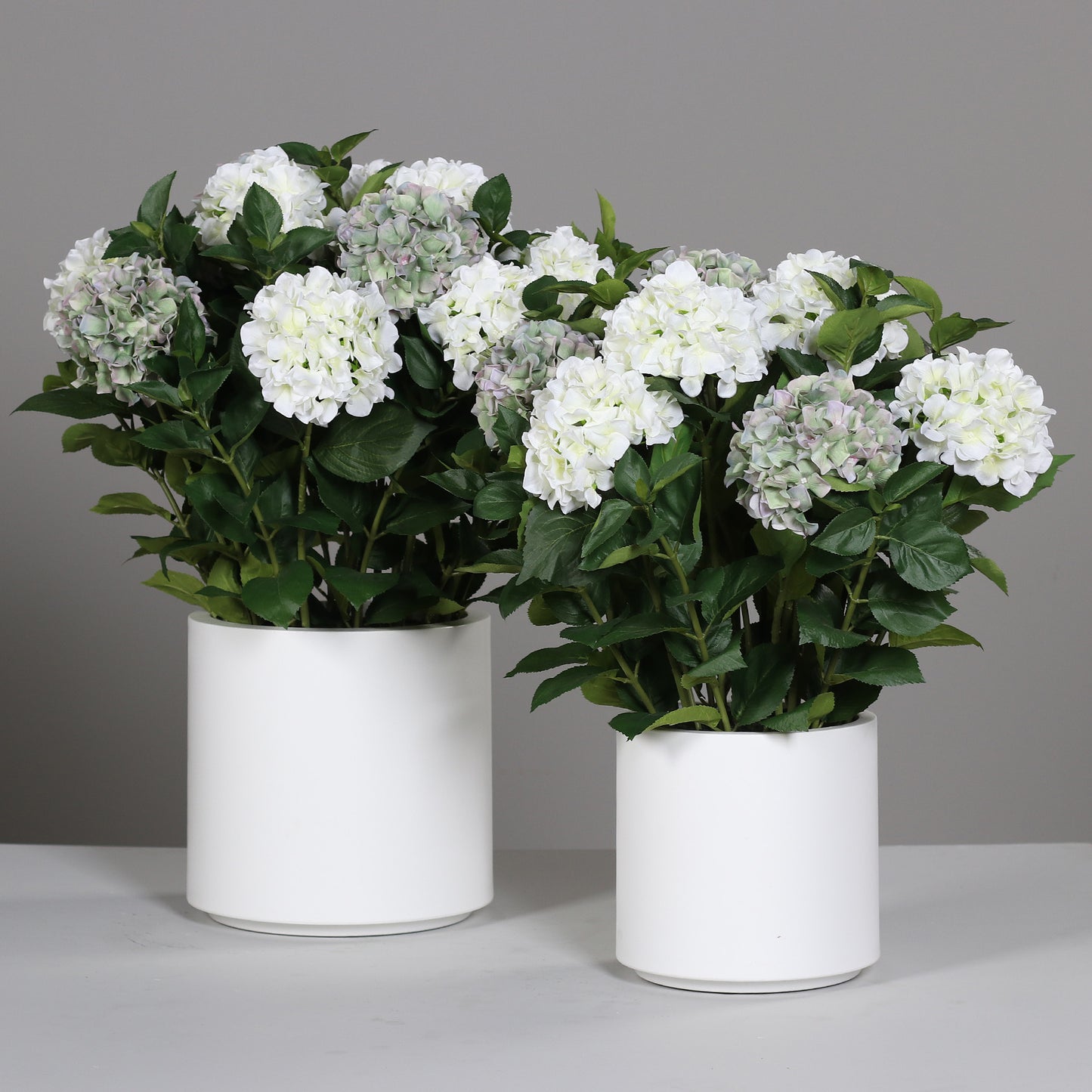 Zwei künstliche Premium Hortensien-Arrangements im Topf weiß auf Tisch